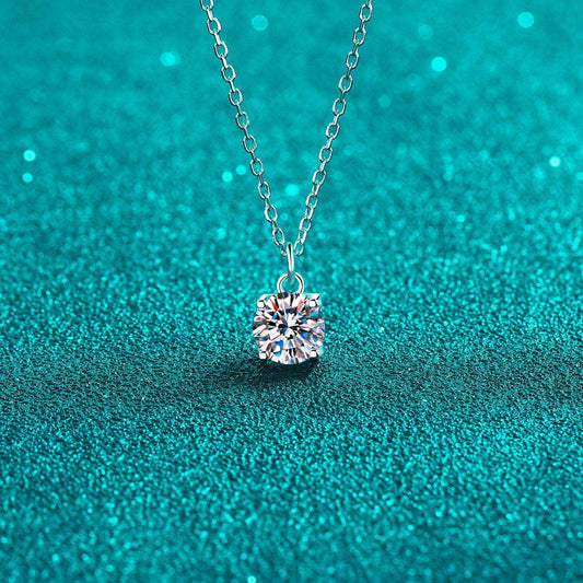 Single sparkling crystal pendant necklace on a silver chain against a vibrant teal background with glittering highlights.