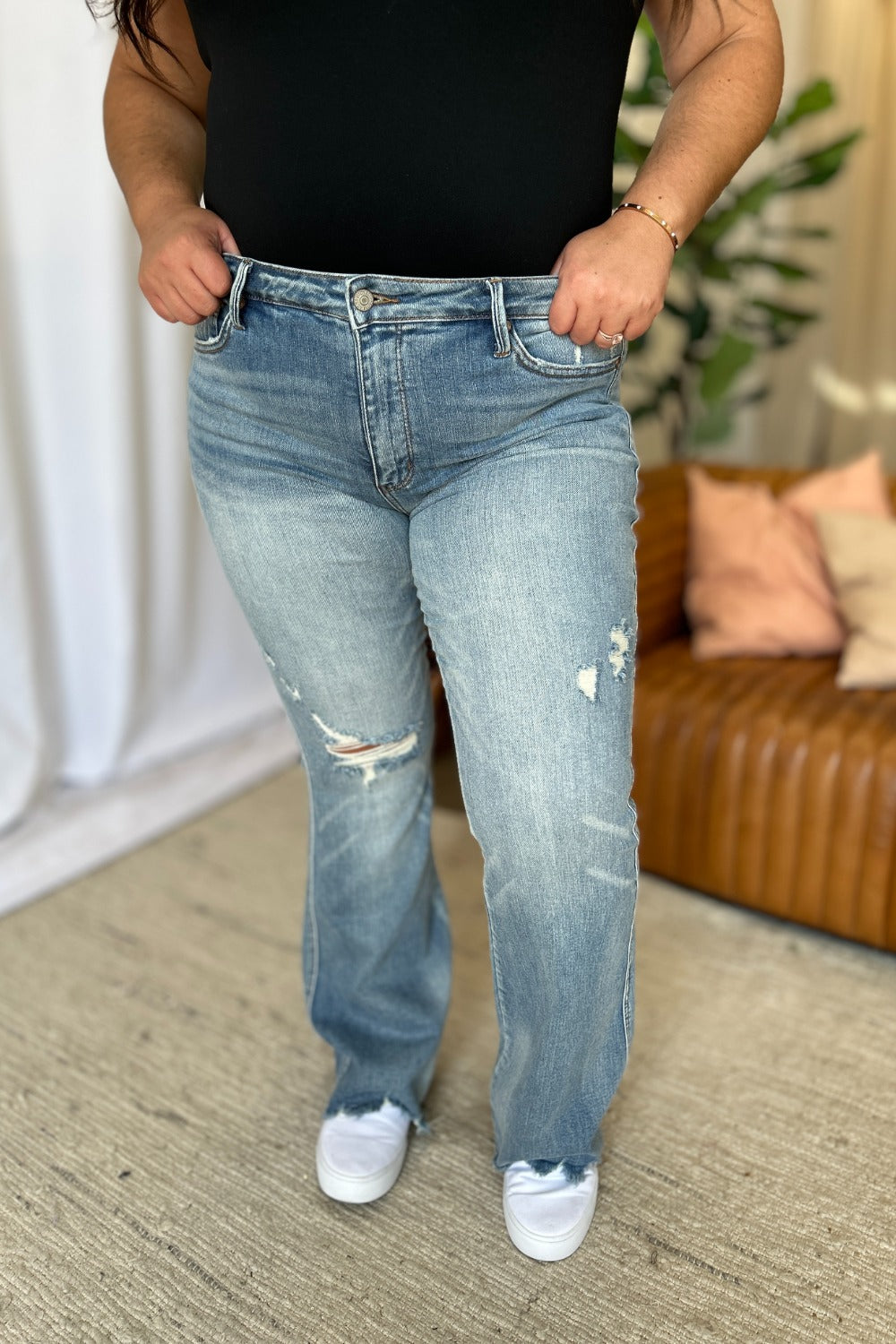 a woman standing in a living room with her hands in her pockets