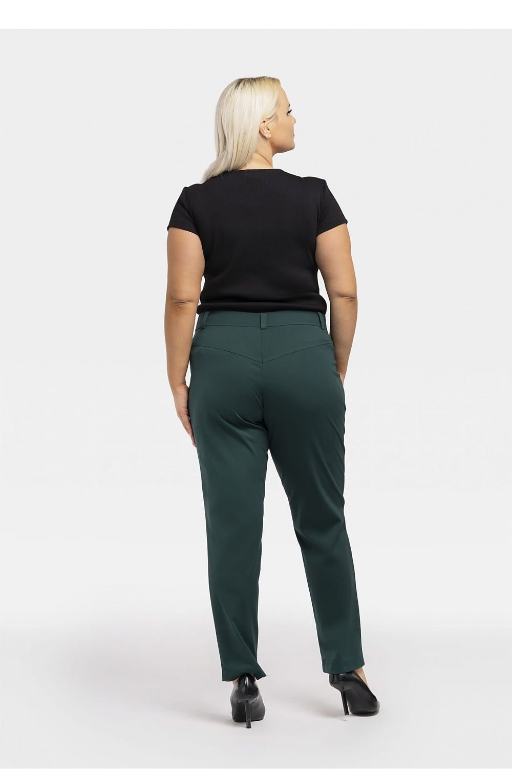 a woman in a black top and green pants