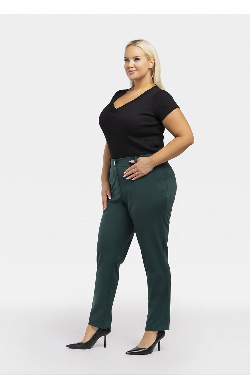 a woman in a black top and green pants