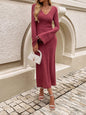 a woman in a pink sweater dress standing on a cobblestone street