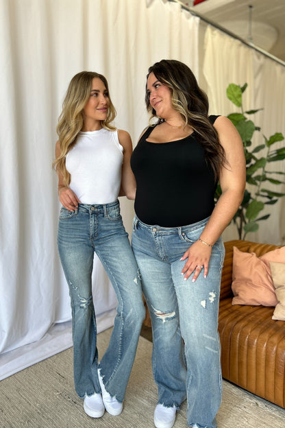 two women standing next to each other in jeans