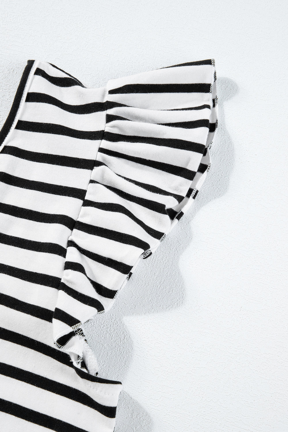 a black and white striped shirt laying on top of a white wall