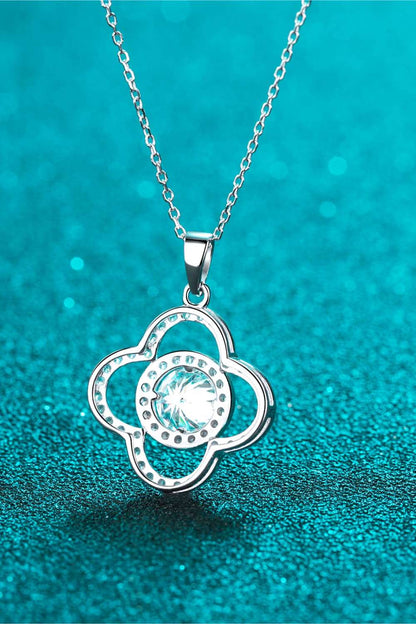 Elegant silver necklace with a sparkling cubic zirconia pendant in the shape of a flower, placed on a teal glittery background.