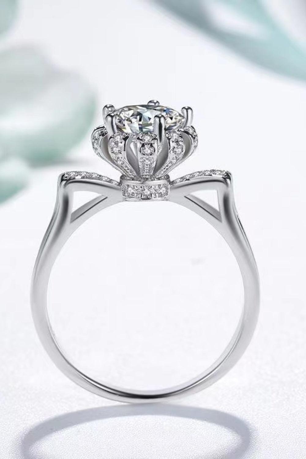 Elegant diamond engagement ring with regal crown design. Sparkly moissanite center stone in sterling silver setting.