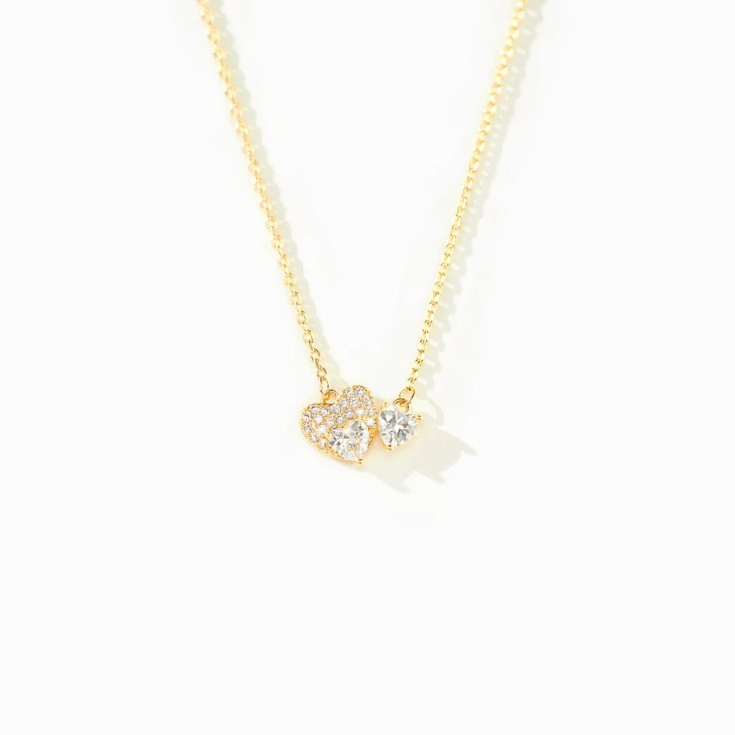 a gold necklace with two hearts on it