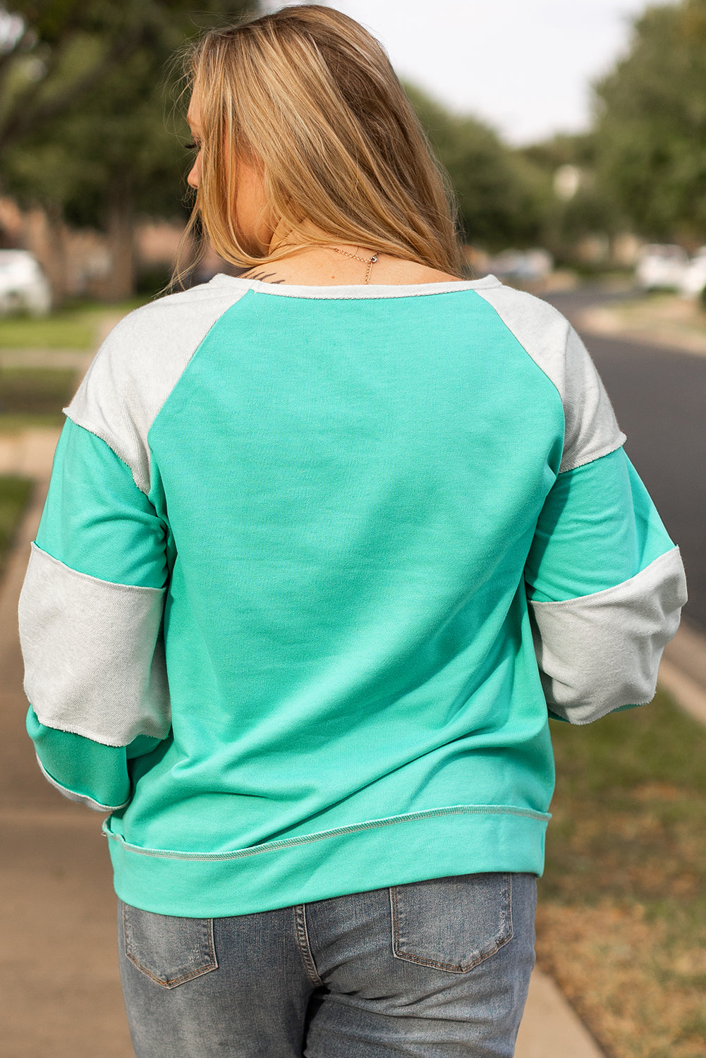 a woman is walking down the sidewalk with her back to the camera