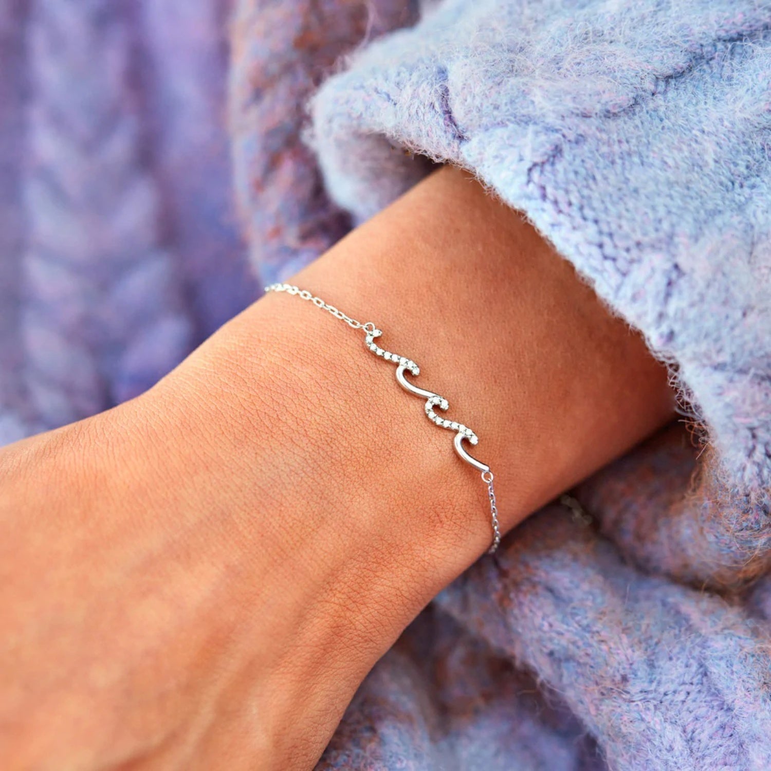 a woman wearing a silver bracelet with three hearts on it