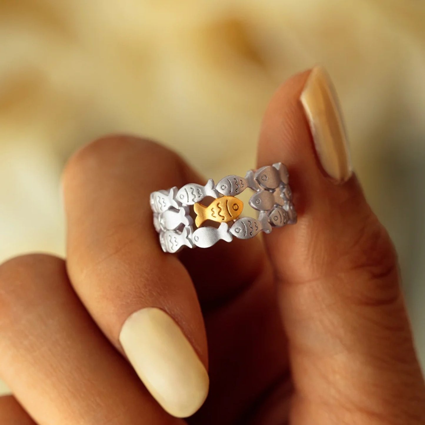 a woman's hand holding a gold and silver ring