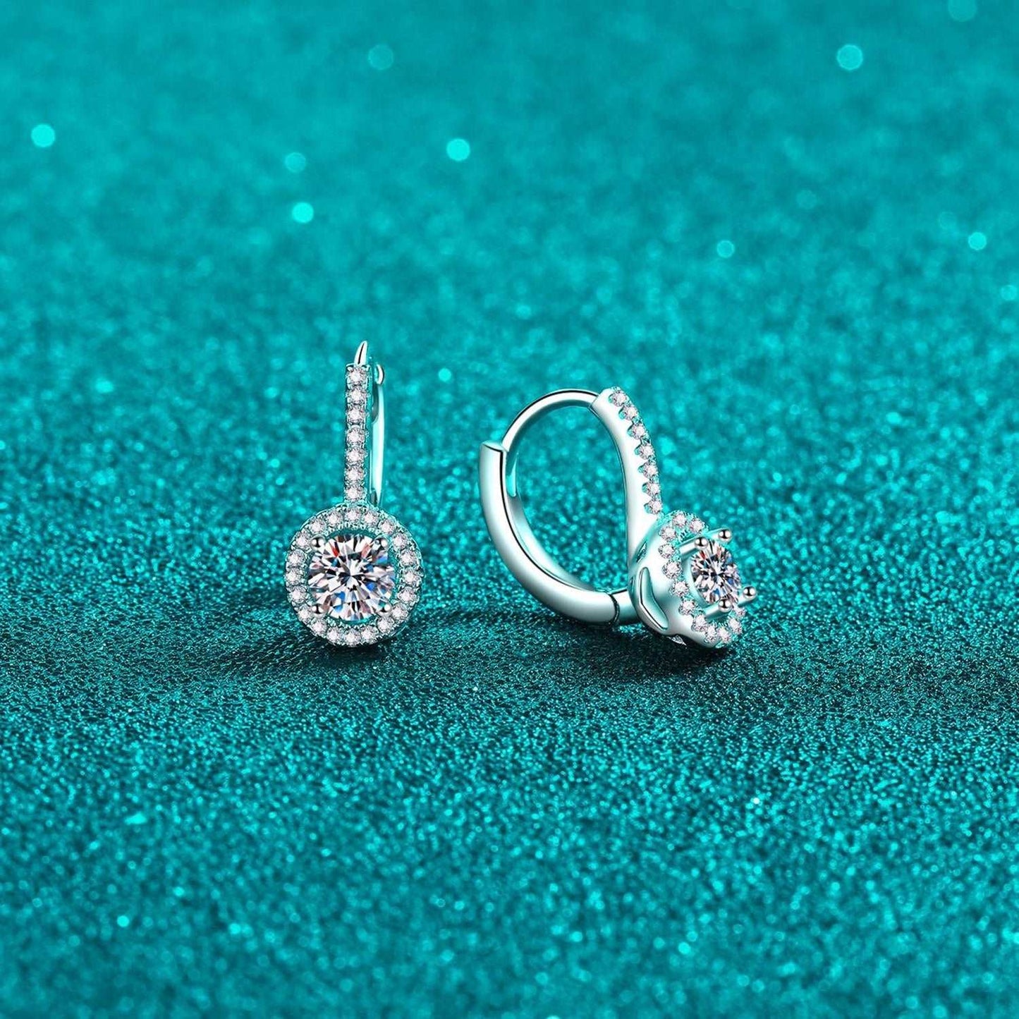 Elegant diamond-studded sterling silver hoop earrings on a teal glitter background, showcasing a luxurious and sophisticated jewelry item.