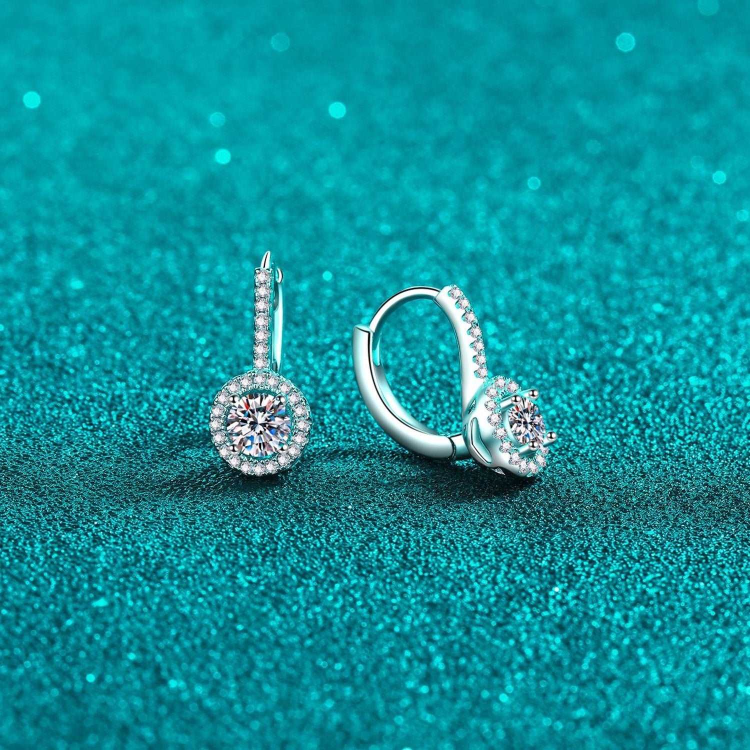 Elegant diamond-studded sterling silver hoop earrings on a teal glitter background, showcasing a luxurious and sophisticated jewelry item.