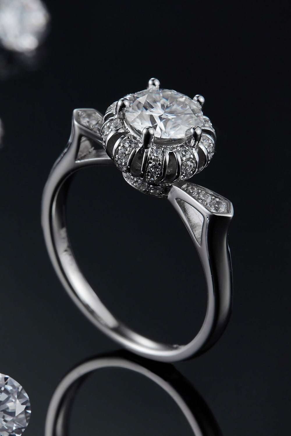 Elegant sterling silver ring with sparkling 1 carat moissanite center stone and intricate floral-inspired band design.