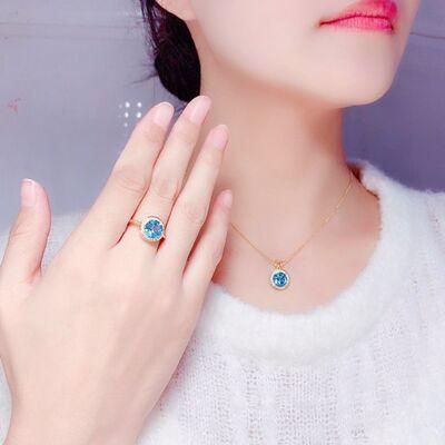 Elegant gold-plated ring and necklace with vibrant blue gemstones displayed against a woman's face and neck.